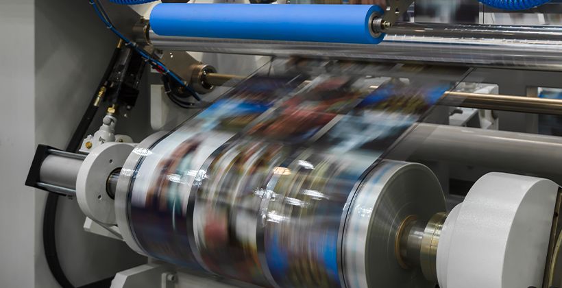 impresora grande ejecutando un rollo de papel largo para imprimir revistas